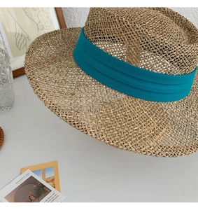 Detailed texture of handmade seagrass sun hat with a wide teal decorative ribbon
