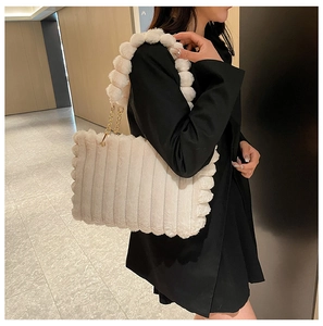 Detail of cream plush tote bag featuring striped texture and fuzzy ball bead shoulder strap