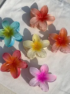 Detailed view of six colorful matte plumeria flower hair claws on white fabric