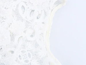 Détail de la broderie en dentelle blanche évidée avec des motifs floraux complexes
