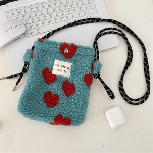 Detail view of blue plush heart crossbody bag with striped strap and snap closure