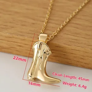 Golden cowboy boot pendant necklace with polished finish on a minimalist wooden base