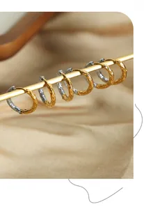 Detail of two-tone hammered texture hoop earrings hanging on a metal bar for display