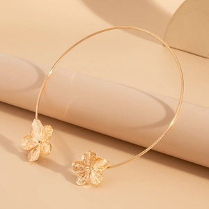 Detailed view of golden metal petal texture on a minimalist floral open collar necklace