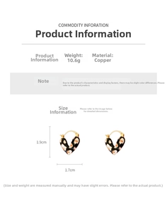 Gros plan détaillé des boucles d'oreilles cœur dorées avec émail noir et motifs fleurs