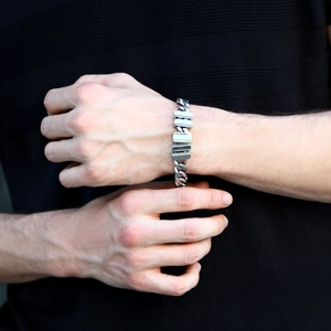 Close-up of men's silver Cuban link bracelet on wrist with polished stainless steel finish