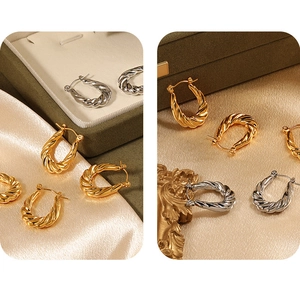 Detailed view of gold and silver twisted rope hoop earrings on luxury silk background