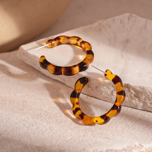 Macro view of C-shaped resin leopard print earrings with wavy edges on stone