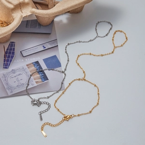 Detail of minimalist stainless steel beaded chain bracelets in gold and silver finish