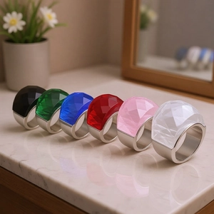 Detail shot of six colorful geometric crystal rings on a white marble surface