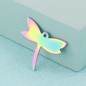 Rainbow stainless steel dragonfly pendant with crystal accents on blue surface