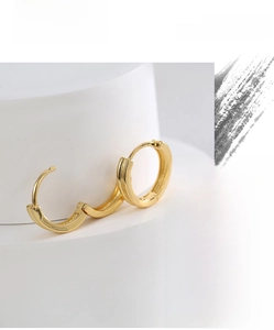 Detailed view of polished gold plated round hoop earrings on a white minimalist pedestal