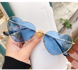 Detail of vintage heart-shaped sunglasses with metal frame and blue tinted lenses