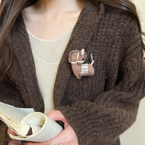 Detail of handcrafted brown fabric pony brooch with white stitching on a knitted cardigan
