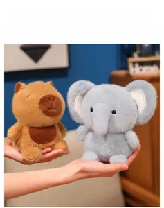 Close-up of small plush capybara and elephant dolls held in hand showing soft fur texture