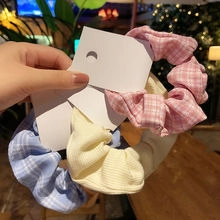 Detailed view of pink plaid, blue plaid and cream yellow scrunchies set on display card