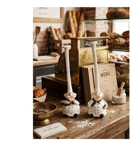 Close-up of resin chef figurines with bread tray and pan in vintage bakery setting