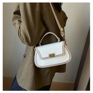 Détail du sac à main en cuir blanc avec fermoir rotatif doré et bandoulière réglable beige