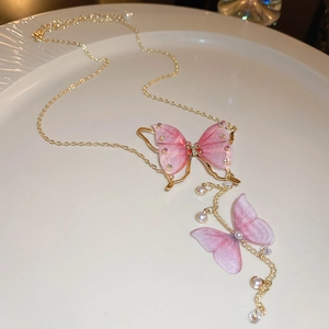 Detail of pink tulle butterfly necklace with gold chain, crystals and pearls on ceramic plate
