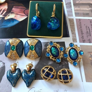 Détail de boucles d'oreilles vintage dorées avec émail bleu et cristaux scintillants