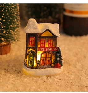 Detail of a light-up resin Christmas fire station with warm LED lights and faux snow decor