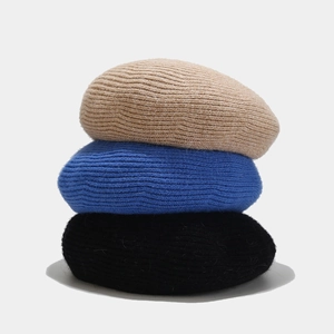 Detailed close-up of ribbed texture on stacked wool knit beret hats in three colors