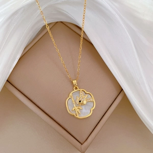 Close-up of gold cloud pendant with white shell inlay and bird pattern on silk