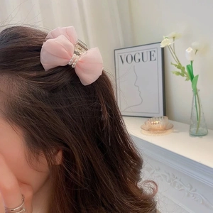 Dettaglio della molletta per capelli con fiocco in organza rosa e perle eleganti