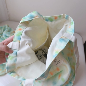 Detailed close-up of the interior pocket and tie-dye canvas texture of the tote bag