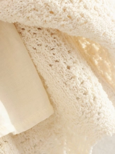 Dettaglio ravvicinato di maglia all'uncinetto crema con fodera interna liscia abbinata