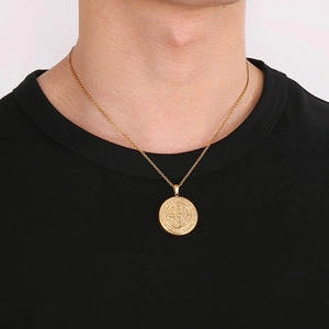 Gros plan d'un pendentif médaille de Saint-Benoît doré avec gravures religieuses