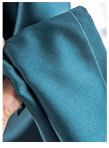 Close-up of deep teal blackout fabric showing heavy texture and elegant drape detail