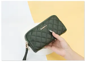 Detail of dark green quilted long wallet with secure double zipper and wrist strap