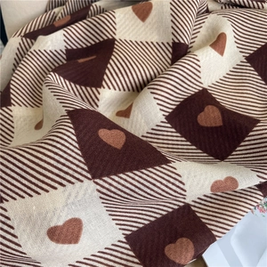 Close-up of checkered cotton-linen scarf with brown heart pattern and soft texture