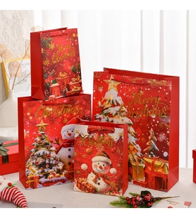 Various sizes of red Christmas gift bags with snowman and tree patterns on the table