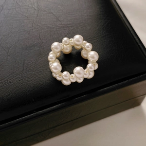 Makro-Detail eines weißen Perlencluster-Rings auf einer schwarzen Leder-Schmuckschachtel