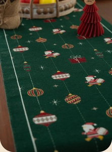 Detail showing dark green woven Christmas table runner with Santa Claus and gift patterns