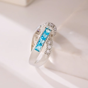 Macro shot of silver ring featuring cross design with square blue stones and white zircon