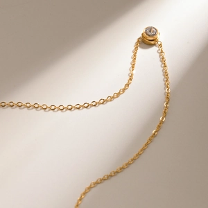Detailed close-up of a gold titanium steel necklace featuring a sparkling zircon pendant