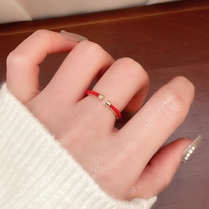 Close-up of a red woven adjustable snake ring on model finger with gold metal accents