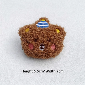 Detailed view of curly brown plush bear brooch with blue striped hat, size 6.5cm x 7cm