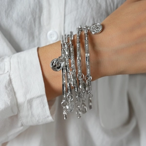 Detailed close-up of multilayer silver bracelets featuring retro coin charms with portrait relief