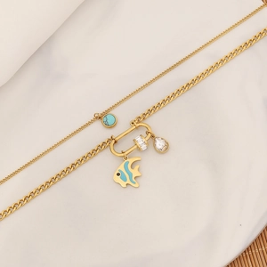 Detail of layered gold necklace featuring turquoise, tropical fish pendant and crystals