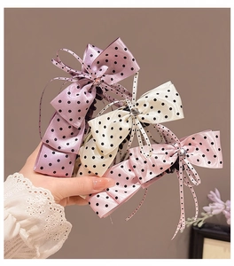 Vue détaillée de barrettes à nœud en satin à pois en rose, crème et lavande chic