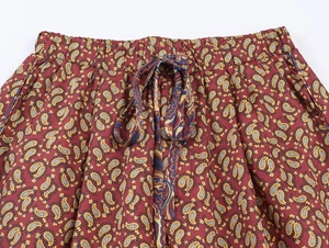 Détail du pantalon bordeaux à motif paisley avec taille élastique et cordon de serrage