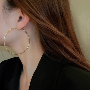 Close-up of minimalist large golden hoop earring worn by a model for a stylish look
