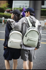 Outdoor shot of couples wearing mumu letter print backpacks in beige and light green