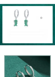 Detailed close-up of 925 sterling silver dinosaur earrings with green pavé zircon stones