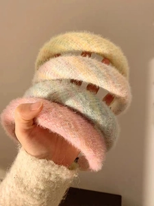 Gros plan de serre-têtes en peluche douce aux tons pastel jaune, rose et menthe
