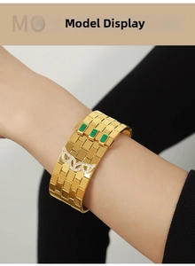 Close-up of 18K gold-plated cuff with green accents and crystal wing detail